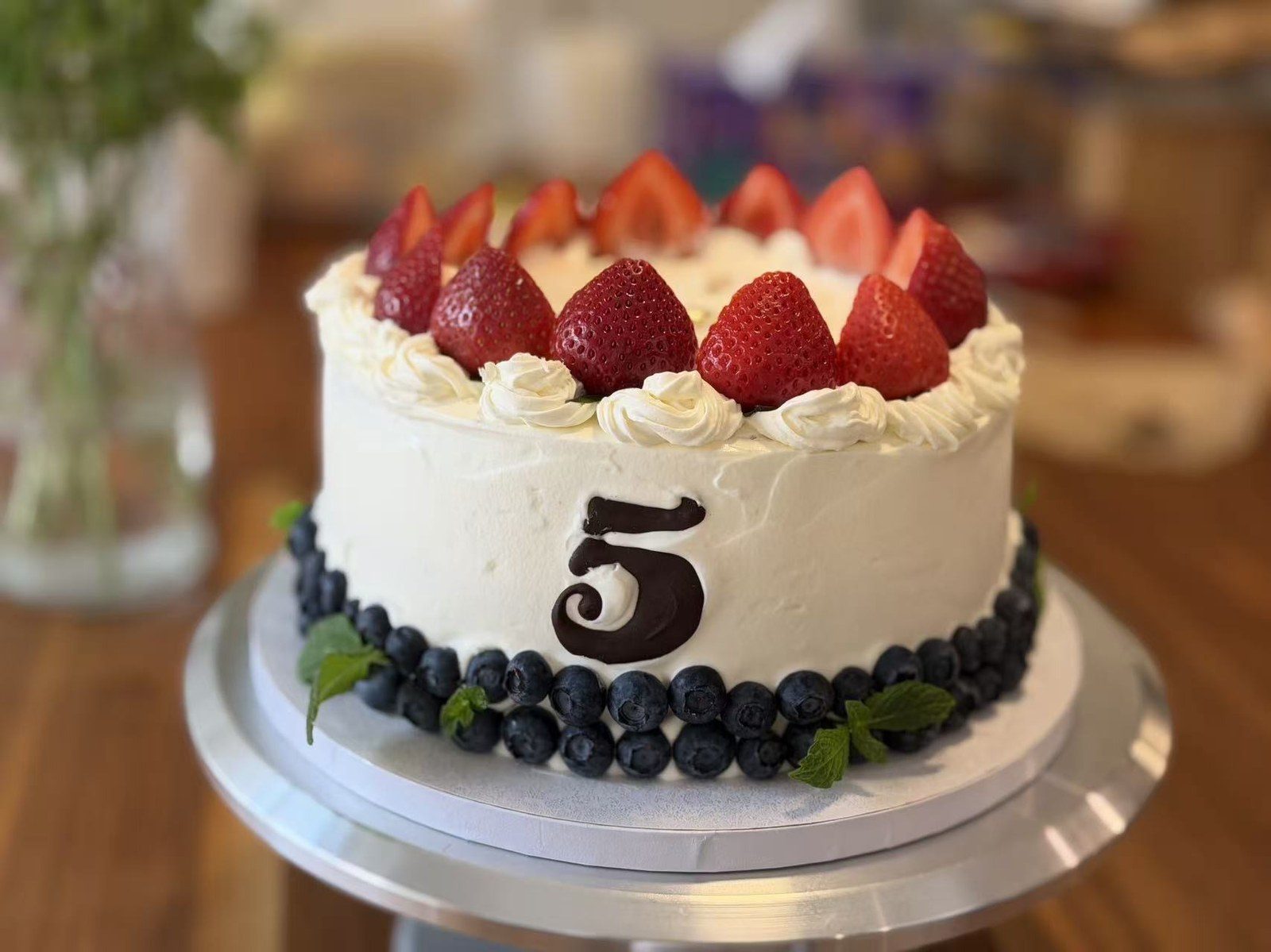 Cake with strawberries on top and blueberries around the base