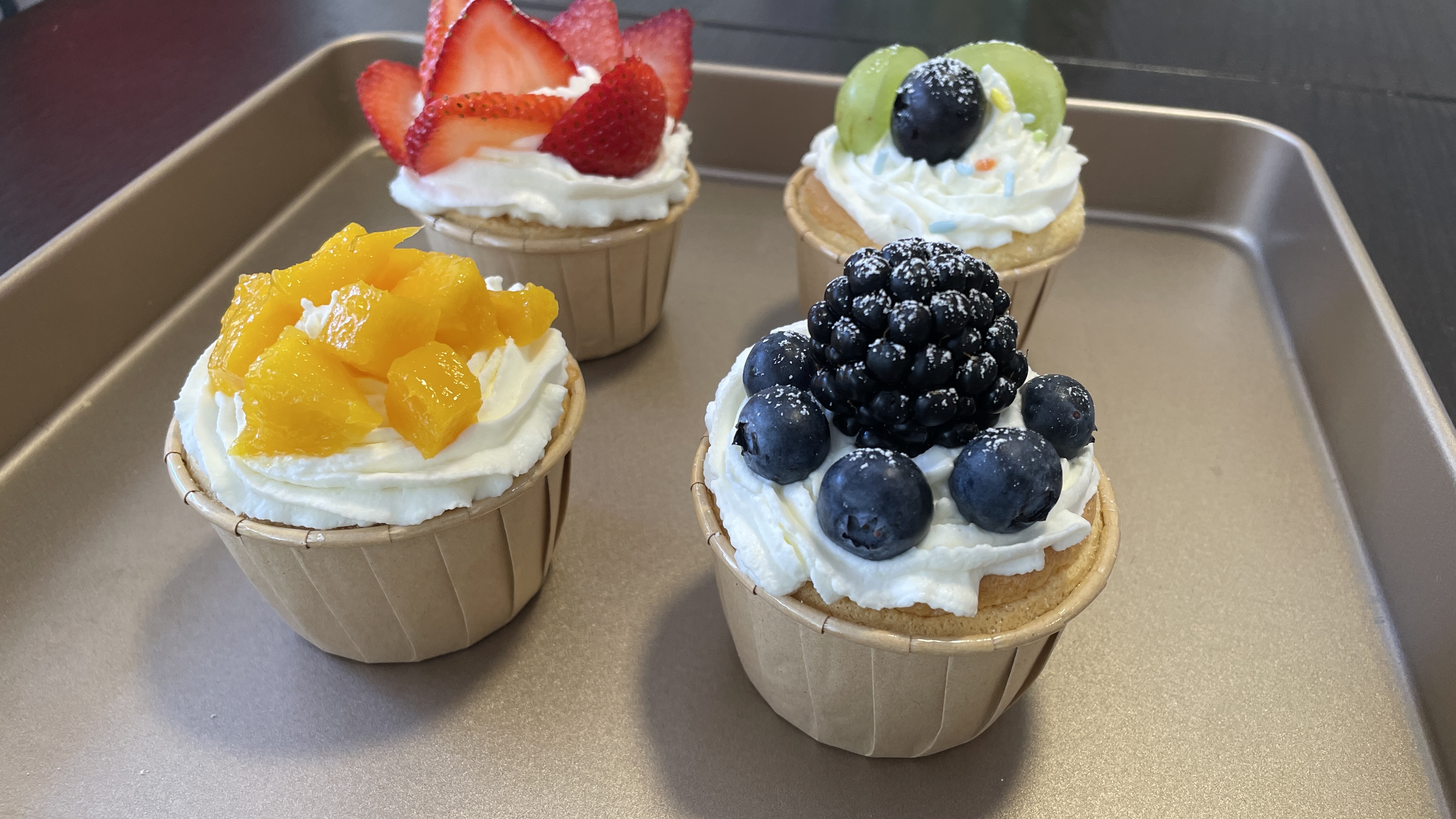 Fruit-topped cupcakes with strawberry, mango, blueberry and blackberry