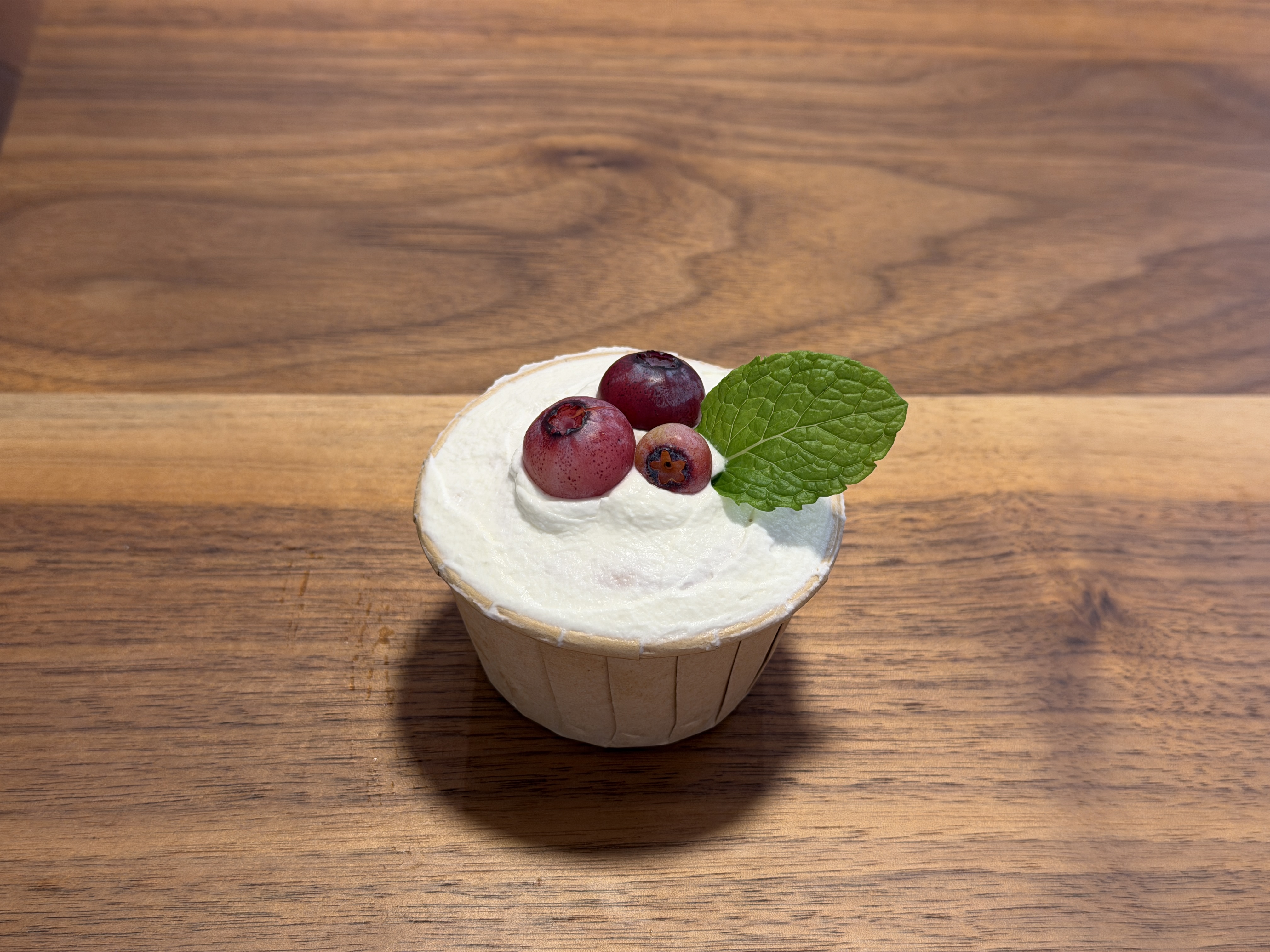 Single cupcake topped with berries and mint