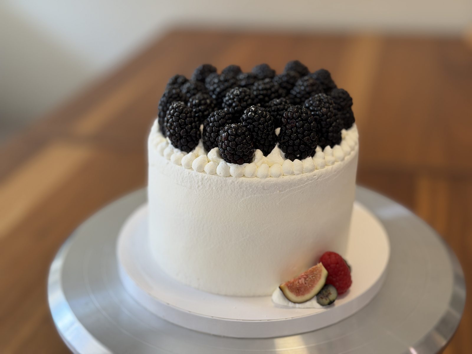 White whipped cream cake piled with fresh blackberries, served with fig and raspberry