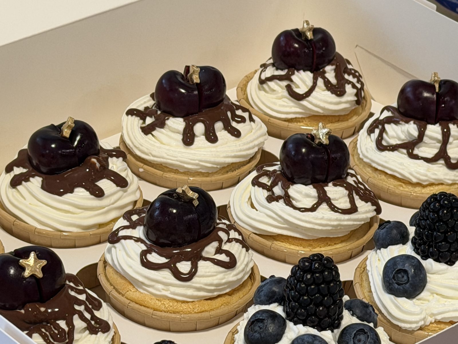 Mini tarts topped with whole cherries and chocolate drizzle