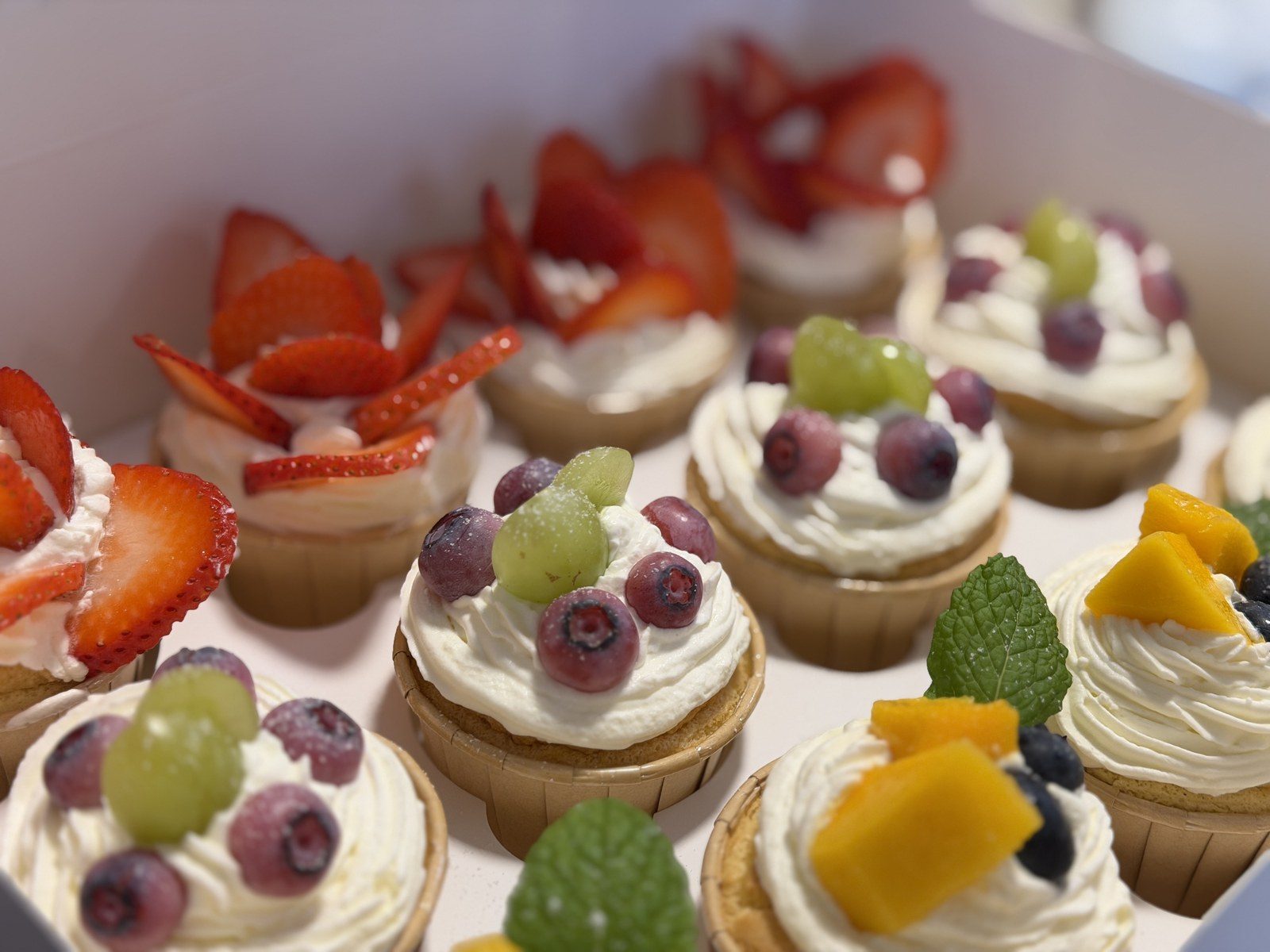 Cupcakes with mixed fruit toppings — strawberry, grape, mango and blueberry