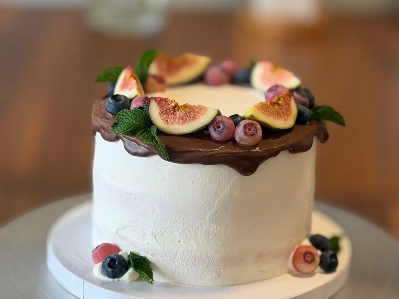 Cake with a chocolate ganache rim, fresh figs, blueberries and mint