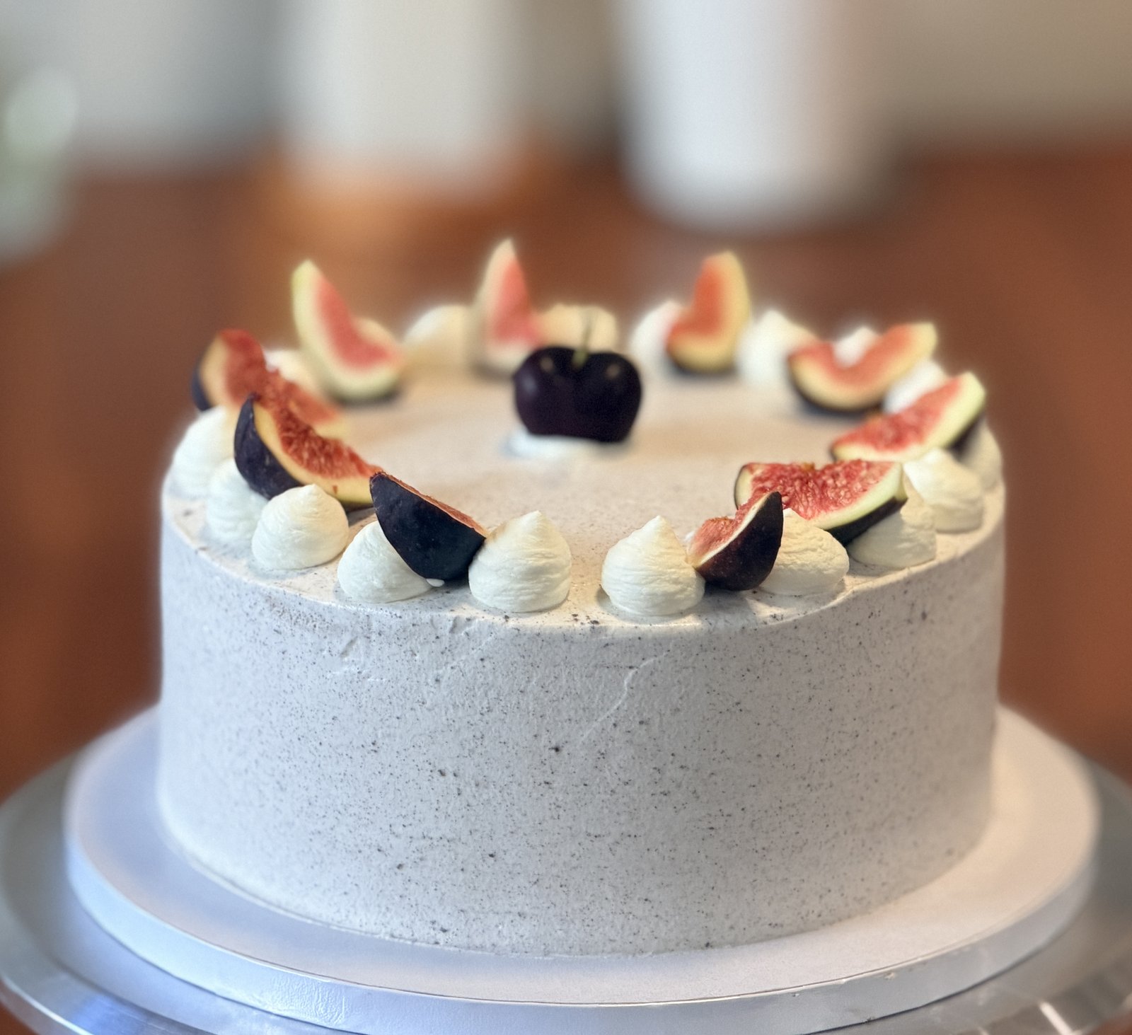 Custom cake with fresh figs, a cherry and whipped cream rosettes