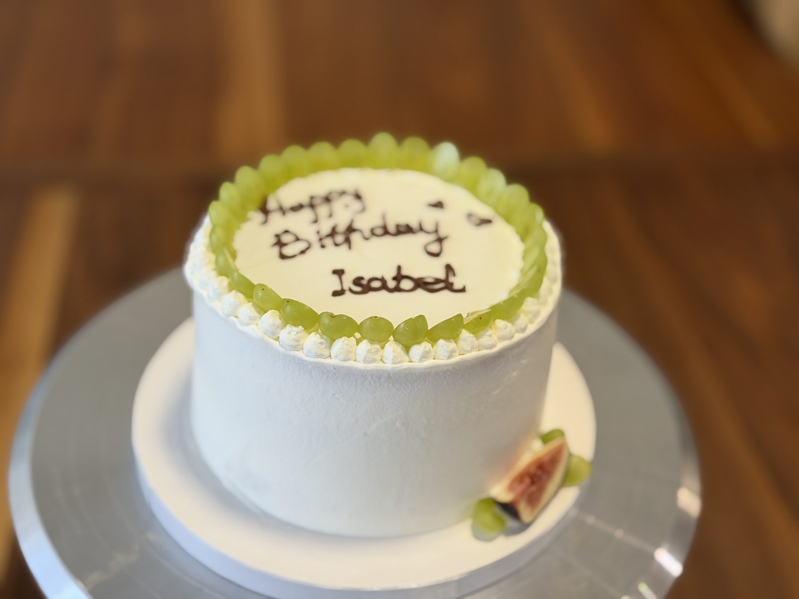 Birthday cake ringed with green grapes and hand-written chocolate lettering