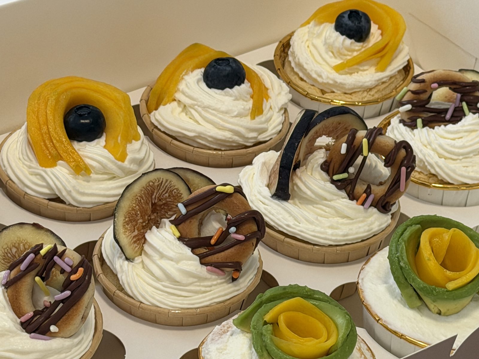 Assorted mini tarts topped with mango, blueberry, fig and chocolate drizzle