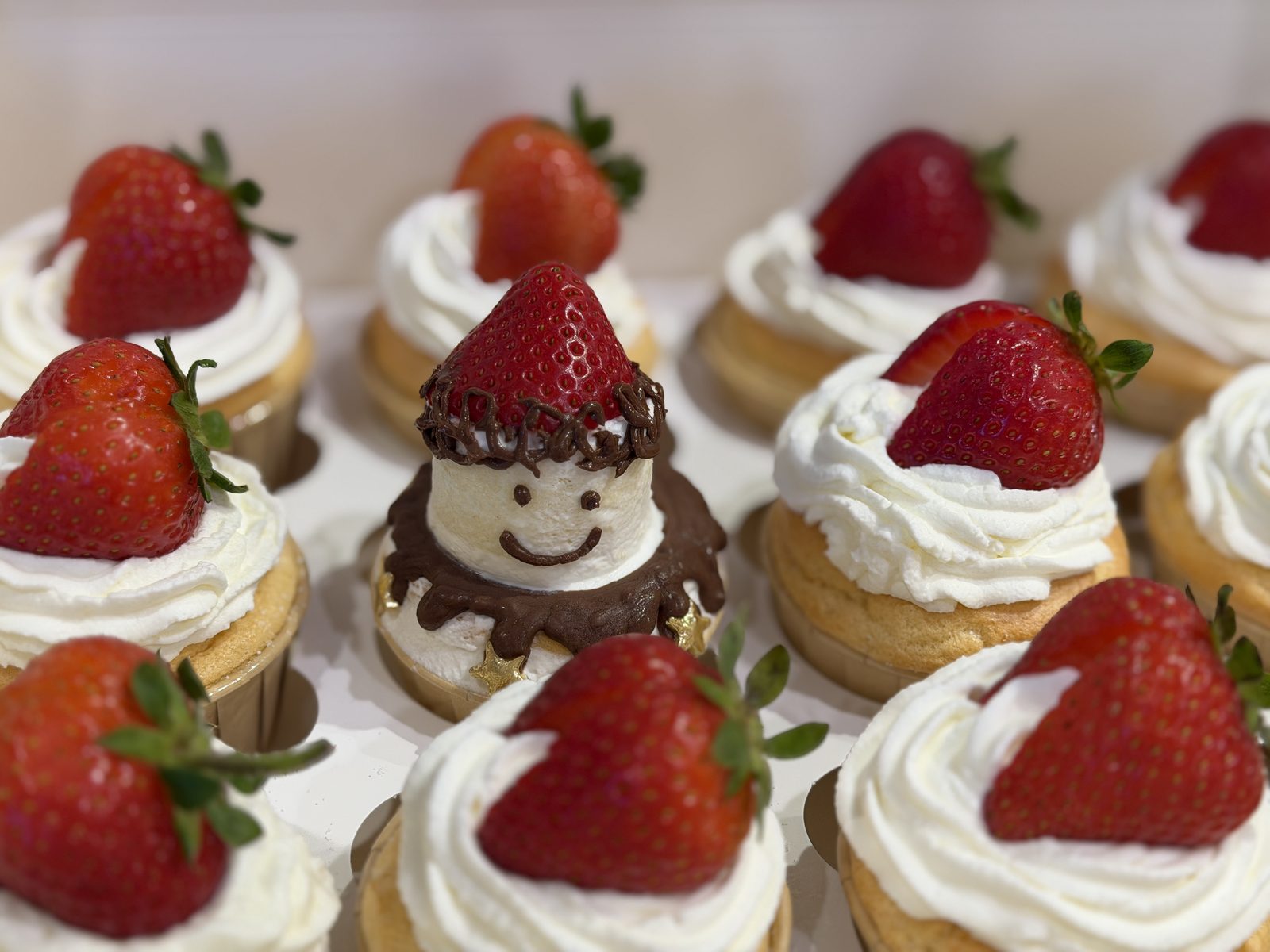 Whipped cream cupcakes topped with whole strawberries, with a marshmallow snowman in the middle